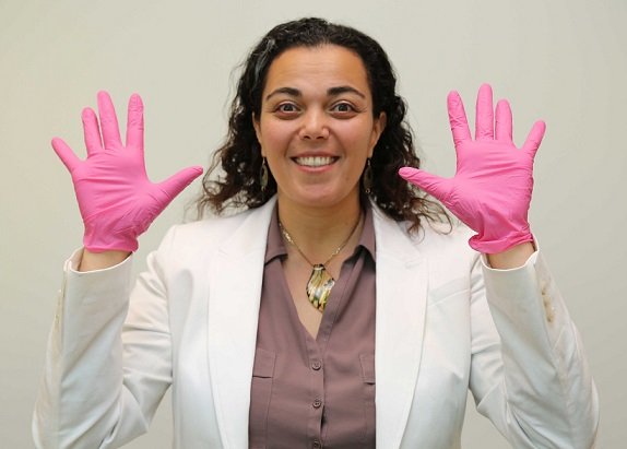 Dr Bodour Salhia wearing pink gloves and smiling