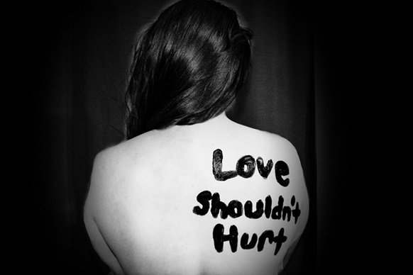 Madonn's Domestic Violence Story _black and white image of woman with writing "Love shouldn't hurt" painted on her back