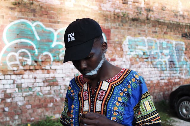 Male African man smoking walking past Graffiti wall_Lindawella and her Loss